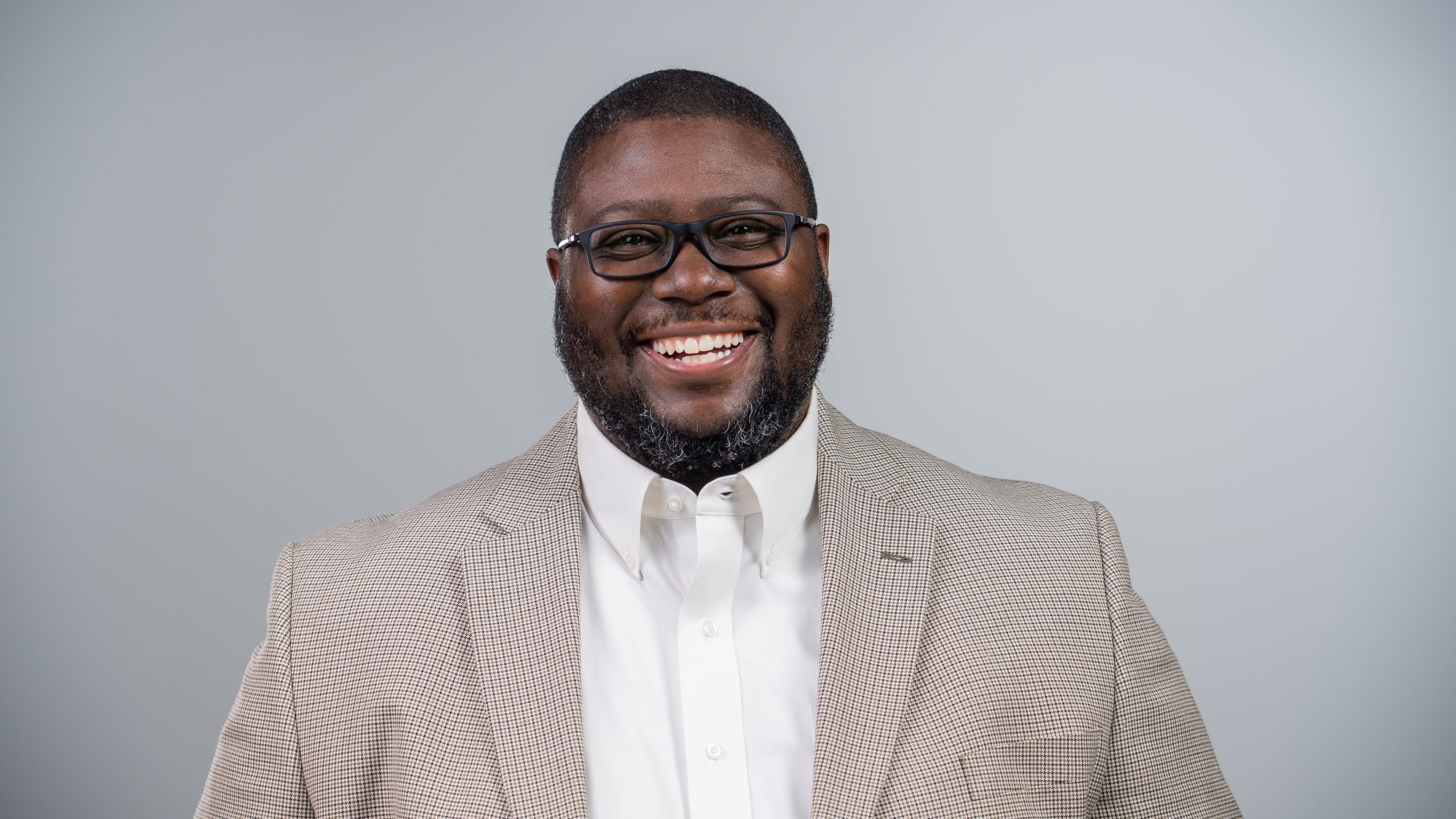 Eric Elliott professional headshot smiling in a beige blazer